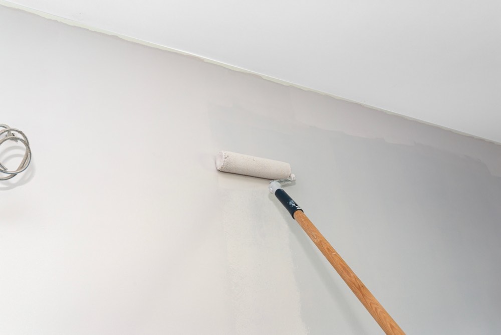 A Kingdom of Coating crew member cutting in paint along a ceiling line in Denver, CO